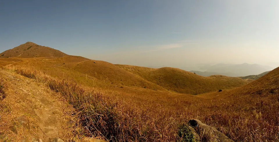 Golden grassy slopes with a footpath on the left under a clear sky.