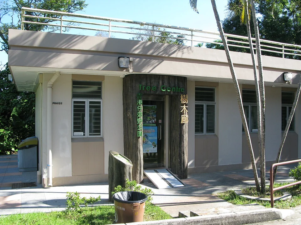 A low blue-and-white building with an awning beside a paved path and shrubs.